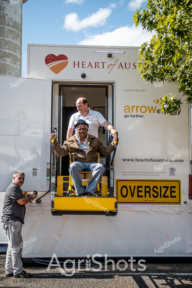 Heart of Australia's mobile medical outreach captures the essence of rural healthcare innovation. A specialized truck equipped with an accessibility lift demonstrates compassionate support for regional communities, featuring the "Heart of Australia" and "Arrow" partnership branding. An older gentleman in a brown jacket is being carefully assisted down the yellow lift platform by medical staff, symbolizing dignity and inclusive healthcare access for remote populations. The crisp blue sky, green foliage, and gleaming white truck create a bright, hopeful atmosphere that underscores the mission of bringing critical medical services to underserved areas. The prominent "OVERSIZE" sign hints at the significant logistical challenges of delivering specialized healthcare to expansive, sparsely populated regions of Queensland. This image powerfully illustrates the commitment to rural wellbeing, showcasing how targeted mobile health services can bridge geographical and accessibility gaps for communities far from major medical centers.
