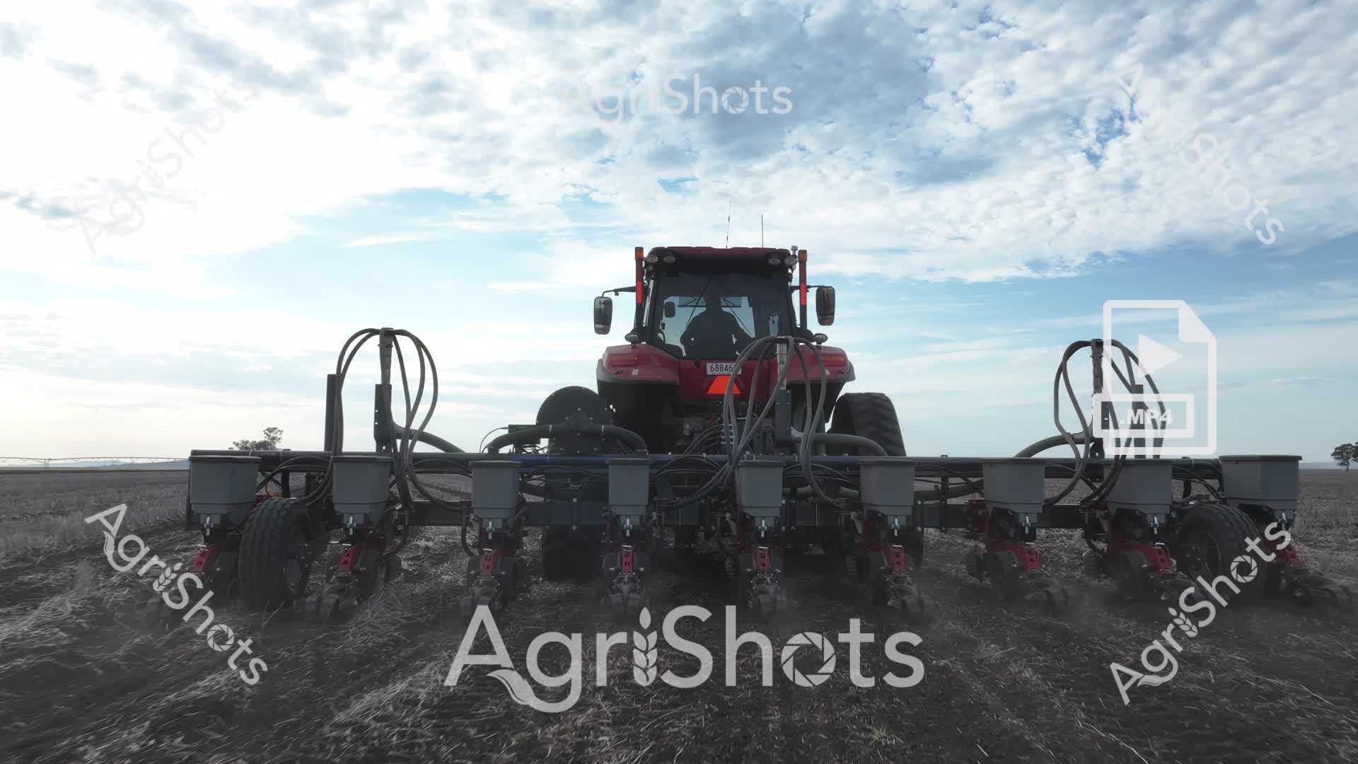Precision agriculture unfolds across a vast, cloud-dappled prairie, where a robust red Case IH tractor anchors a sophisticated multi-row planter. Gleaming steel seeding units stretch wide, poised to deposit seeds with millimeter-perfect accuracy into the prepared dark earth. The expansive sky - a tapestry of soft blues and mottled whites - frames this technological marvel of modern farming, symbolizing the intersection of cutting-edge engineering and traditional agricultural practice. Each hydraulic row unit stands ready, suspended on robust frames, representing the pinnacle of agricultural efficiency and innovation. The monochromatic landscape emphasizes the vibrant crimson of the tractor, a bold statement of technological prowess against the subtle greys and browns of the rural terrain. This image captures the essence of contemporary Australian broadacre farming - a testament to precision, scale, and the relentless pursuit of agricultural productivity.