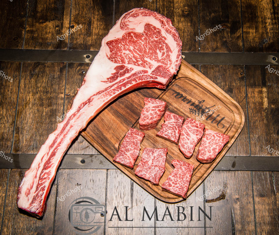Mayura Station's prized Wagyu beef takes center stage in this exquisite composition of prime cuts. A magnificent, marbled ribeye bone-in cut stretches dramatically across a wooden cutting board, its intricate web of fat promising unparalleled tenderness and flavor characteristic of top-tier Wagyu. Nestled beside the impressive primary cut, perfectly cubed portions showcase the meat's exceptional marbling - rich crimson and creamy white fat intertwining in a delicate, appetizing pattern. The rustic wooden backdrop and cutting board from The collection evoke the artisan craftsmanship of premium Australian beef production, highlighting the meticulous care taken from pasture to plate. Each carefully portioned cube represents the pinnacle of South Australian livestock breeding, a testament to Mayura Station's commitment to producing world-class Wagyu beef. The rich, deep tones of the wood and the spectacular red-and-white marbling create a visual narrative of agricultural excellence, inviting viewers to appreciate the extraordinary quality of Australian beef.