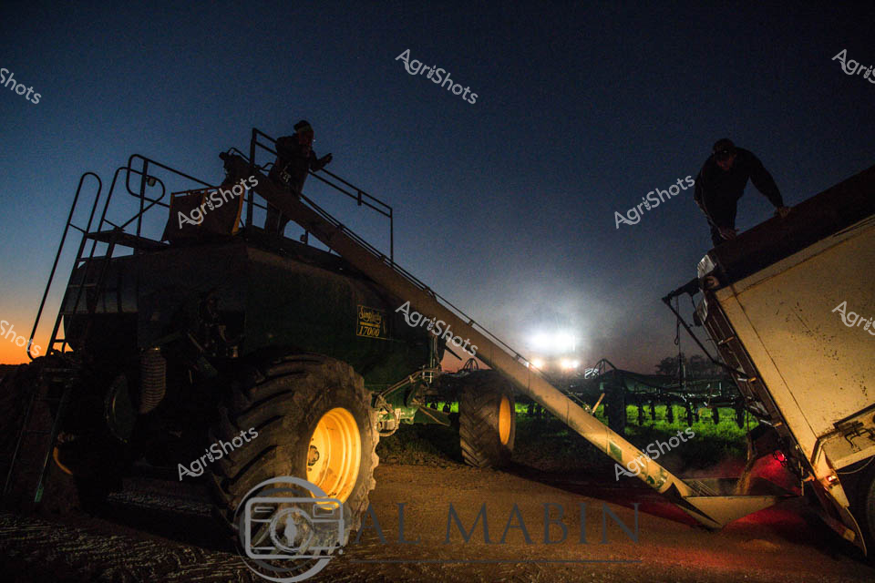Twilight descends on the expansive Queensland agricultural landscape, casting long shadows across precision farming equipment. A massive air seeder and grain cart stand silhouetted against the deep blue evening sky, their imposing mechanical forms illuminated by powerful work lights that create dramatic pools of brightness. Skilled operators navigate the high-clearance machinery, strategically positioning the complex agricultural implements for the next phase of crop planting. The gleaming yellow wheels of the heavy equipment catch the last golden rays of sunset, while the machine's intricate technical components reflect the sophisticated technology driving modern broadacre farming. Trimble guidance systems and advanced tracking mechanisms hint at the cutting-edge precision agriculture transforming Australian rural production. The scene captures a moment of quiet intensity - the pause between daylight and darkness, between preparation and action, embodying the methodical and technologically advanced nature of contemporary agricultural practices in Queensland's vast farming regions.